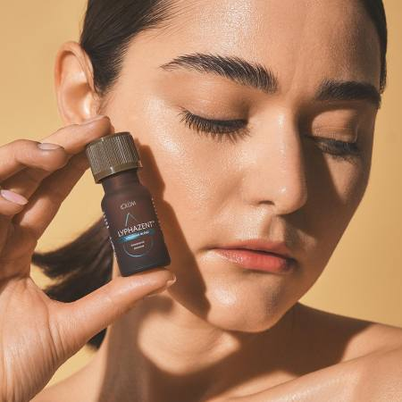 LYPHAZENT™ Lolûm – femme tenant le flacon d'huile drainante près de son visage