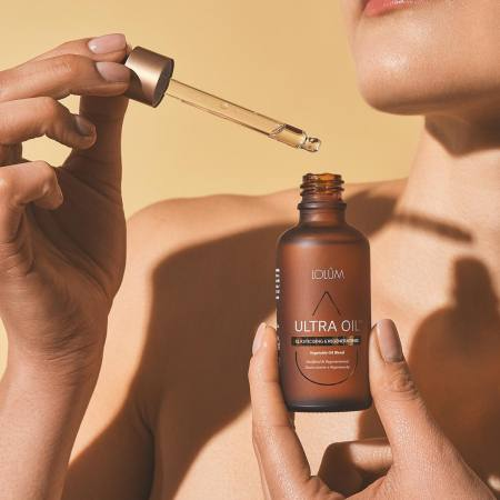 ULTRA OIL™ Lolûm – mains tenant le flacon compte-gouttes d'huile assouplissante et régénérante