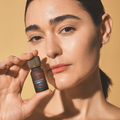DYNAZENT™ Lolûm – femme tenant le flacon d'huile énergisante près de son visage